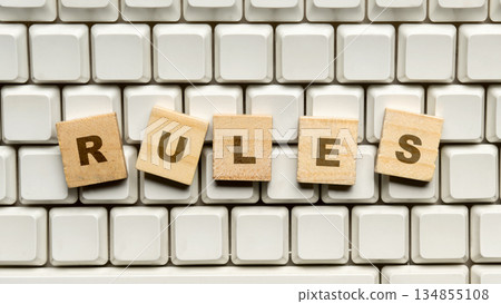 Closeup image of wooden blocks with letters spelling the word "Rules" arranged on a computer keyboard. Concept of rules, compliance, and governance Closeup image of wooden blocks with letters spelling the word "Rules" arranged on a computer keyboard. Concept of rules, compliance, and governance 134855108