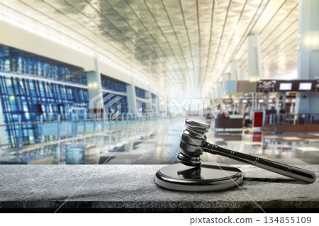 Gavel for justice and the law in an airport departure hall, suggesting a global travel or international legal issue. Concept of rules, compliance, and governance Gavel for justice and the law in an airport departure hall, suggesting a global travel or international legal issue. Concept of rules, compliance, and governance 134855109