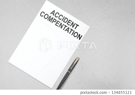 White sheet of paper with the words "Accident Compensation" printed on it, accompanied by a pen, all placed on a neutral gray background. Concept of Accident Compensation White sheet of paper with the words "Accident Compensation" printed on it, accompanied by a pen, all placed on a neutral gray background. Concept of Accident Compensation 134855121
