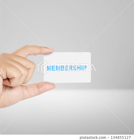 Hand holding a membership card with the word "MEMBERSHIP" printed in blue on the card. The background is a soft gray. Concepts of access, privilege, and loyalty Hand holding a membership card with the word "MEMBERSHIP" printed in blue on the card. The background is a soft gray. Concepts of access, privilege, and loyalty 134855127
