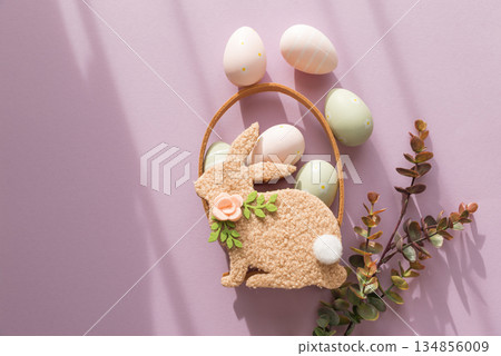 Pastel Easter Bunny Basket with Eggs and Flowers on Lavender Background 134856009