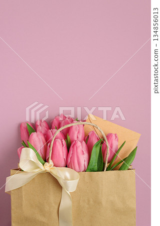 Gift Bag with Pink Tulips and Greeting Envelope on Pink Background. Valentine's or Mother's Day Celebration 134856013
