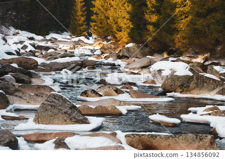 Snow blankets the rocks along the Jizera River, marking the border between Czechia and Poland. A serene winter evening casts a peaceful glow over the landscape. Snow blankets the rocks along the Jizera River, marking the border between Czechia and Poland. A serene winter evening casts a peaceful glow over the landscape. 134856092