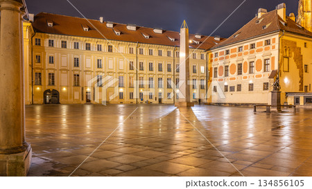 The Mrakotin Monolith towers over Prague Castle's lit courtyard at night, highlighting its stunning architecture in a peaceful setting, accentuated by street lamps and reflections on wet pavement. The Mrakotin Monolith towers over Prague Castle's lit courtyard at night, highlighting its stunning architecture in a peaceful setting, accentuated by street lamps and reflections on wet pavement. 134856105