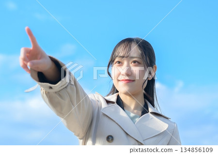 Woman pointing with blue sky in the background Woman pointing with blue sky in the background 134856109