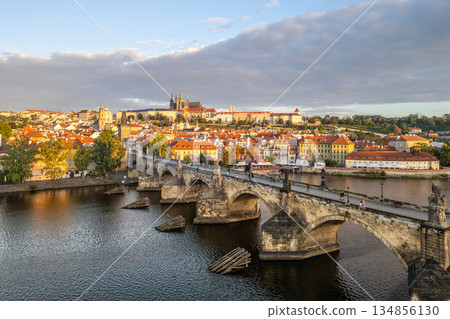 The beauty of Prague Castle rising above the Vltava River, with Charles Bridge in the foreground as the morning sun casts a warm glow over the cityscape. The beauty of Prague Castle rising above the Vltava River, with Charles Bridge in the foreground as the morning sun casts a warm glow over the cityscape. 134856130