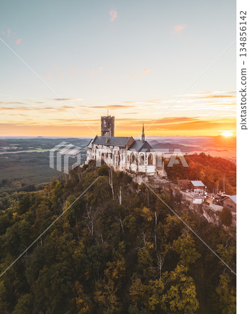 Bezdez Castle stands majestically on a hilltop, its medieval ruins bathed in warm sunset light. Surrounded by lush greenery, it offers a breathtaking view of the Czech landscape during dusk. Bezdez Castle stands majestically on a hilltop, its medieval ruins bathed in warm sunset light. Surrounded by lush greenery, it offers a breathtaking view of the Czech landscape during dusk. 134856142