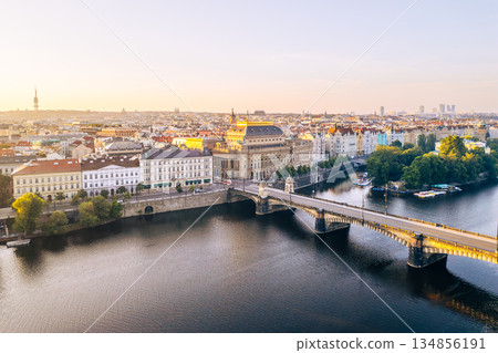 The National Theatre stands prominently along the Vltava River in Prague, capturing the golden tones of sunset. 134856191