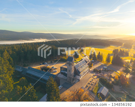 Kralovka Lookout Tower stands tall in the Jizera Mountains, offering stunning views of autumn foliage and surrounding landscapes at sunrise, reflecting a peaceful natural beauty. 134856192