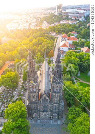 Golden morning light bathes Vysehrad Basilica of St. Peter and St. Paul, highlighting its architectural beauty and surrounding greenery in Prague, Czechia. A tranquil start to the day. 134856193