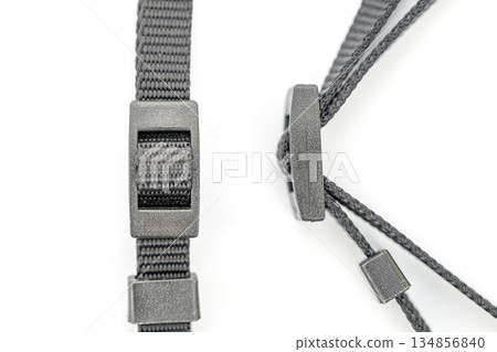 A close-up shows two adjustable black nylon straps with plastic adjusters against a white background. 134856840