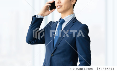 Smiling male businessman talking on a smartphone 134856853