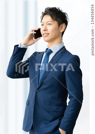 Smiling male businessman talking on a smartphone 134856854