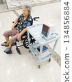 Senior woman sitting in a wheelchair having her blood pressure measured with a digital medical monitor in a hospital. Healthcare and medical concept representing elderly care, patient monitoring, reha 134856884