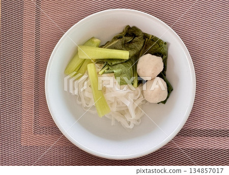 Delicious mouth-watering Asian noodles with meatballs in a white plate on the table Delicious mouth-watering Asian noodles with meatballs in a white plate on the table 134857017