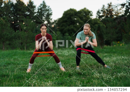 Fitness enthusiasts engaging in outdoor resistance band workout at sunset 134857294