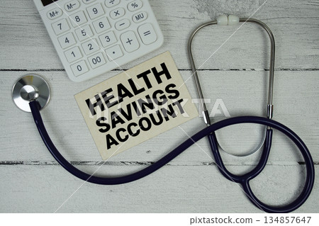 HSA Health savings Account text with Stethoscope and calculator on wooden background 134857647