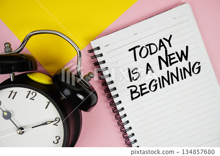 Today Is A New Beginning text written on notepad with alarm clock on pink background 134857680