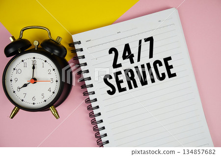24 Hrs 7 Day Service text written on notepad with alarm clock on pink background 134857682