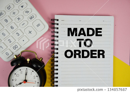 Made to Order text written on notepad with calculator and alarm clock on pink background Made to Order text written on notepad with calculator and alarm clock on pink background 134857687