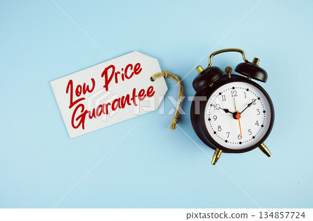 Low Price Guarantee text on price tag with alarm clock on blue background 134857724
