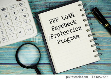PPP LOAN Paycheck Protection Program text on notepad with magnifying glass and calculator on wooden background 134857846