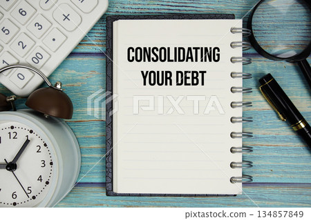 Consolidating Your Debt text on notepad with alarm clock, magnifying glass and calculator on wooden background Consolidating Your Debt text on notepad with alarm clock, magnifying glass and calculator on wooden background 134857849