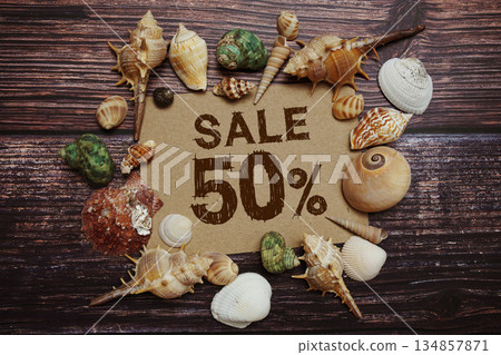 Sale 50% off sign decorated with seashells on a wooden background Sale 50% off sign decorated with seashells on a wooden background 134857871
