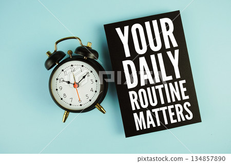 Your Daily Routine Matters text with easel and alarm clock on blue background Your Daily Routine Matters text with easel and alarm clock on blue background 134857890