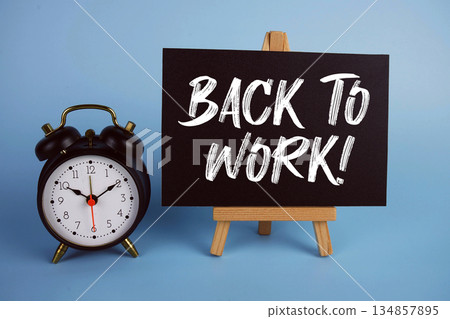 Back To Work! text with easel and alarm clock on blue background 134857895