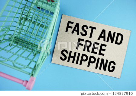 Fast and Free Shipping text on paper card with trolley shopping cart on blue background Fast and Free Shipping text on paper card with trolley shopping cart on blue background 134857910