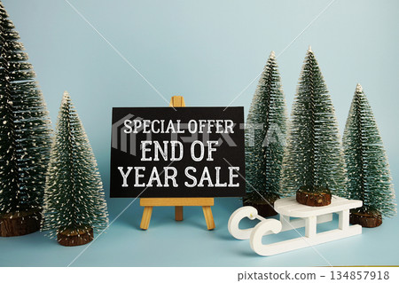 End of Year Sale text with easel and Christmas tree on blue background End of Year Sale text with easel and Christmas tree on blue background 134857918