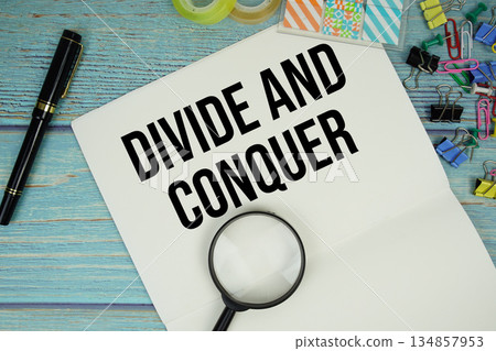 Divide And Conquer text on a paper surrounded by office supplies and magnifying glass on a blue wooden surface Divide And Conquer text on a paper surrounded by office supplies and magnifying glass on a blue wooden surface 134857953