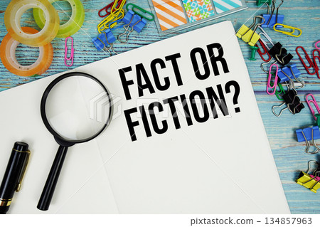 Fact Or Fiction? text on a paper surrounded by office supplies and magnifying glass on a blue wooden surface Fact Or Fiction? text on a paper surrounded by office supplies and magnifying glass on a blue wooden surface 134857963