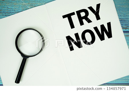 Try Now text written on notepad with magnifying glass flat lay on wooden background 134857971
