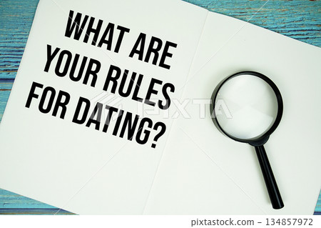 What Are Your Rules For Dating? text written on notepad with magnifying glass flat lay on wooden background 134857972