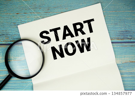 Start Now text written on notepad with magnifying glass flat lay on wooden background Start Now text written on notepad with magnifying glass flat lay on wooden background 134857977