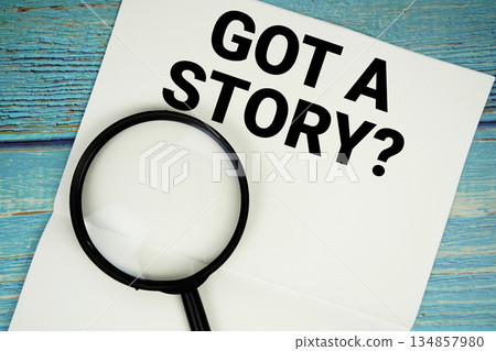 Got A Story? text written on notepad with magnifying glass flat lay on wooden background 134857980
