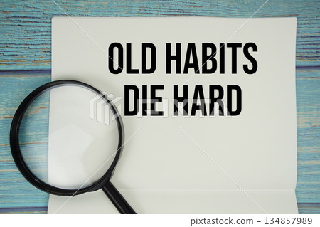 Old Habits Die Hard text written on notepad with magnifying glass flat lay on wooden background Old Habits Die Hard text written on notepad with magnifying glass flat lay on wooden background 134857989
