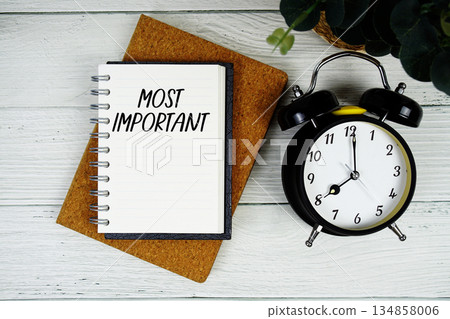 Most Important text written on notepad with alarm clock on wooden background Most Important text written on notepad with alarm clock on wooden background 134858006