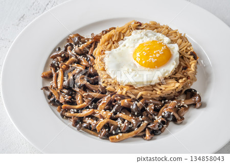Savory fried rice topped with umami Shimeji mushrooms and golden sunny egg 134858043