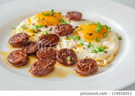 Hearty fried eggs served with caramelized chorizo slices and fresh scallion garnish 134858051