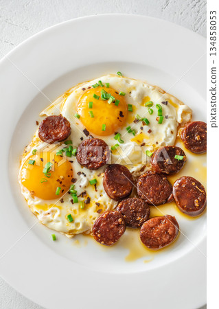 Hearty fried eggs served with caramelized chorizo slices and fresh scallion garnish 134858053