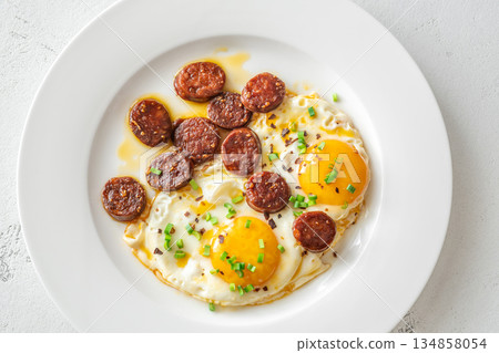 Hearty fried eggs served with caramelized chorizo slices and fresh scallion garnish 134858054