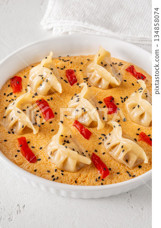 Steamed gyoza dumplings in creamy Tom Yum sauce with sesame garnish 134858074