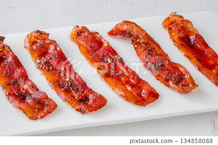 Billionaire bacon strips glazed with pepper and chili flakes on minimalist plate 134858088