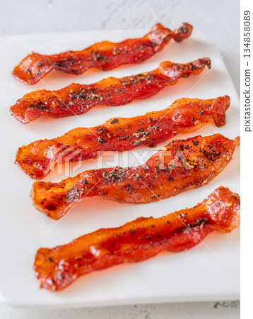 Billionaire bacon strips glazed with pepper and chili flakes on minimalist plate 134858089