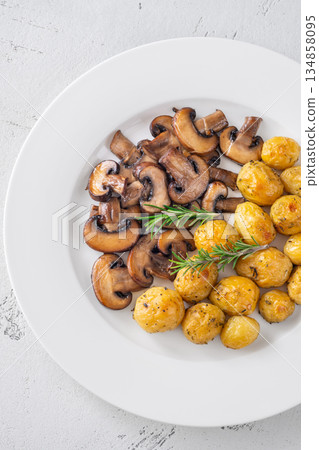 Roasted baby potatoes with sauteed mushrooms and rosemary on minimalist white plate 134858095