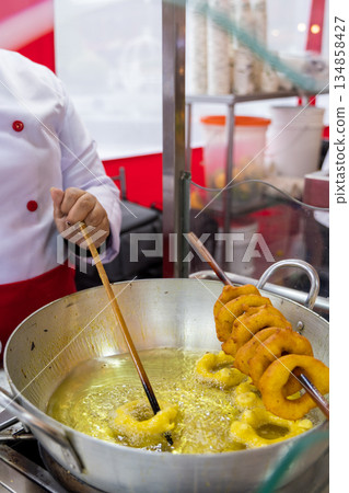 A woman is cooking picarones in a pan A woman is cooking picarones in a pan 134858427