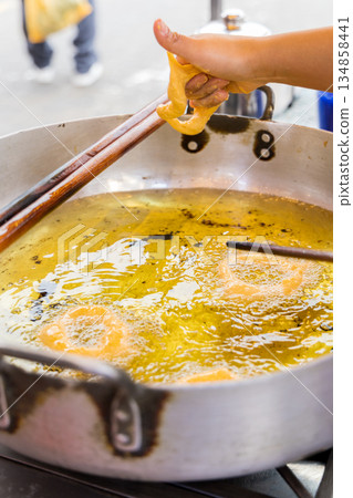 A woman is cooking picarones in a pan 134858441